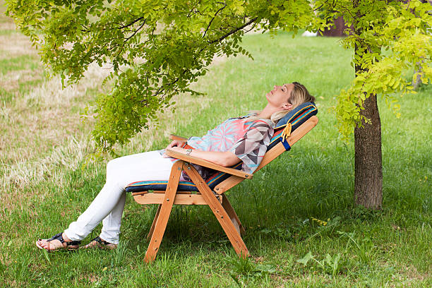 istock Mature woman lying relaxed on deck chair under tree (XXL) 182802070