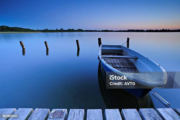 Calm Lake With Fishing Boat Tied To Dock After Sunset Stock Photo - Download Image Now