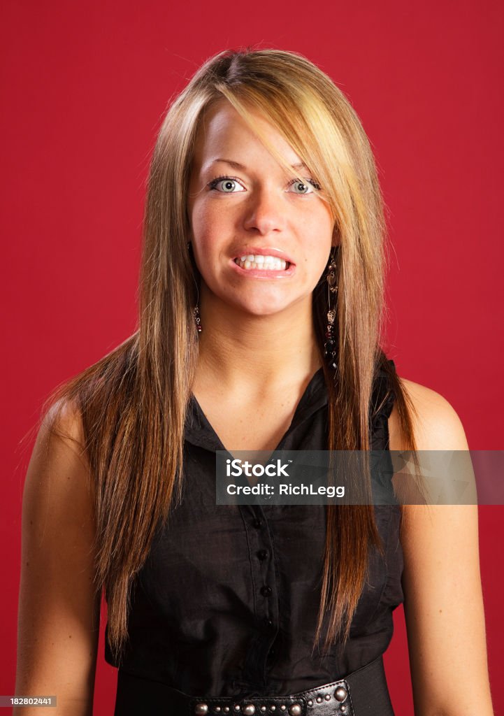 Teenage Girl Clenching Teeth A studio portrait of a teenage girl clenching her teeth. Adult Stock Photo