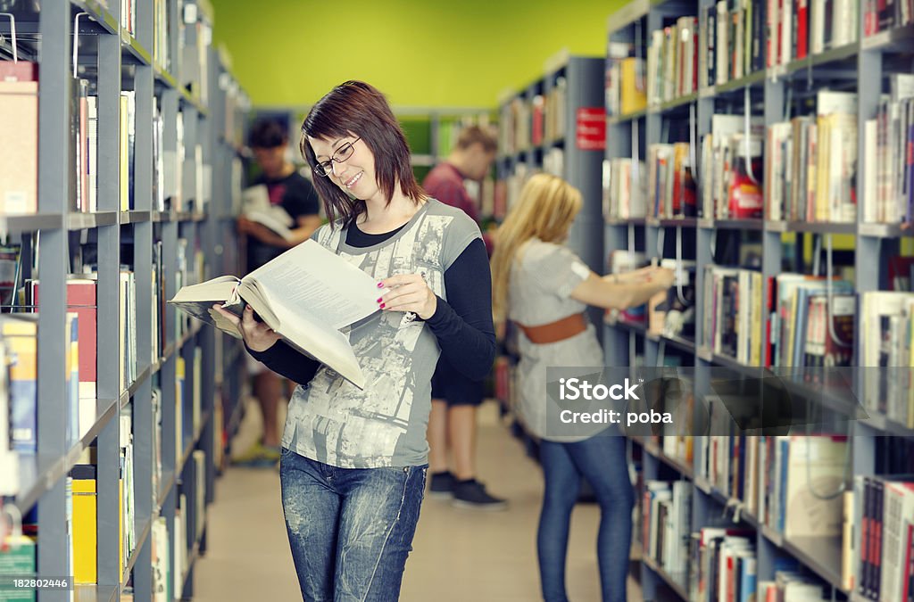 Estudantes procurando estudo materiais na biblioteca. - Foto de stock de Adolescente royalty-free