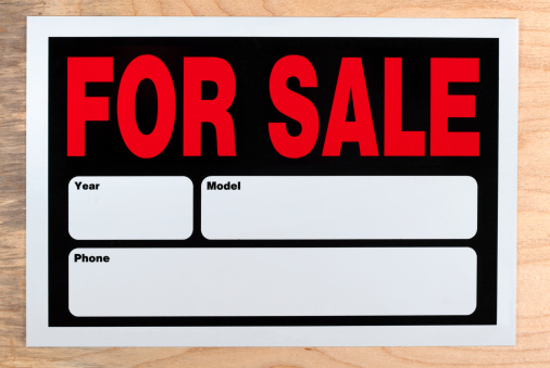 for sale sign against a wooden background