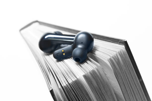 istock Wireless headphones and book. Audiobook concept. 1828025657