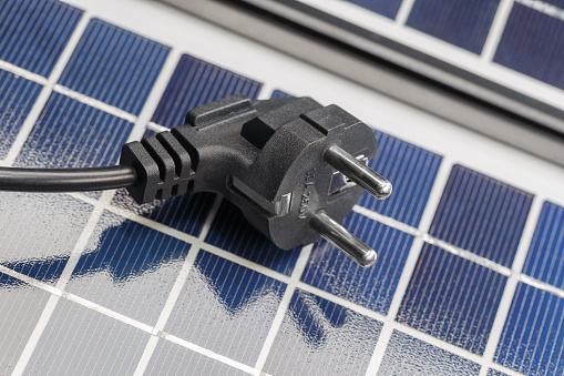 An electric plug lies on the solar panels. The concept of environmentally friendly solar energy.