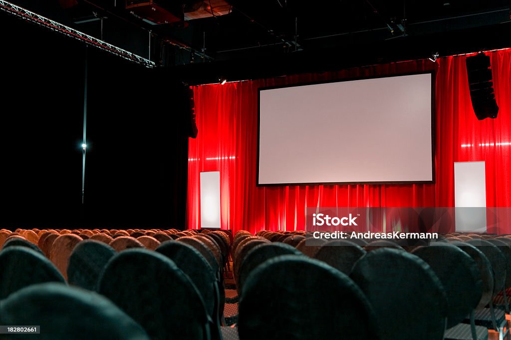 Empty large auditorium with a red curtain and blank screen Convention hall with video screen and copy space for text or logo Stage - Performance Space Stock Photo