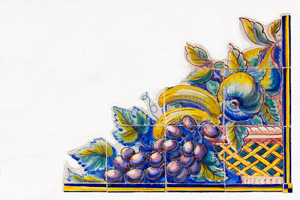 Iberian Fruit Tiles "Iberian, antique polychrome ceramic tile, painted with a basket of fruit of grapes, bananas, apples and pears. Tiles set into a rendered and whitewashed painted wall in a triangular format. Will make a good decorative corner piece, and plenty of blank space for your text and graphics. ." antique fruit bowl stock pictures, royalty-free photos & images
