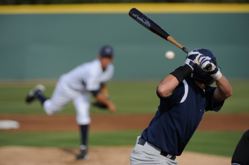 A baseball player looks at a pitch during a game.