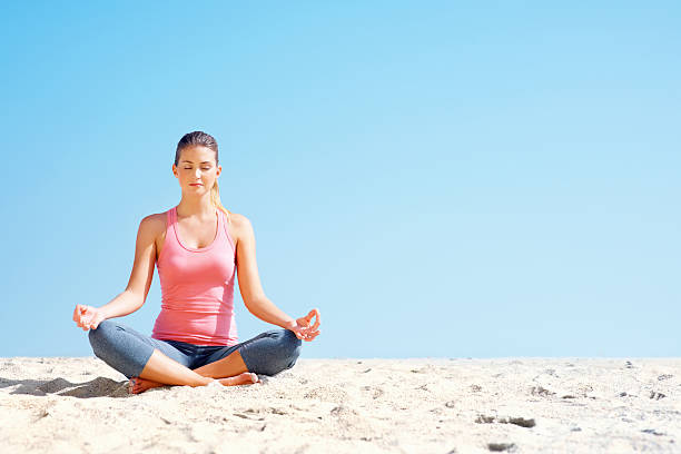 istock Female meditating in lotus position at beach 182802951