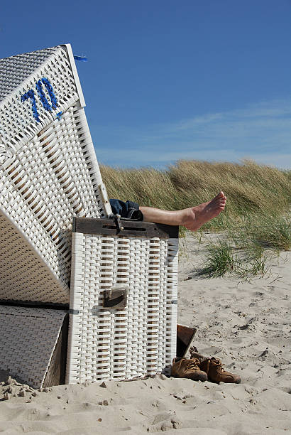 relaxing on the baltic beach relaxing man in a lonely beach chair in front of the dike hooded beach chair stock pictures, royalty-free photos & images