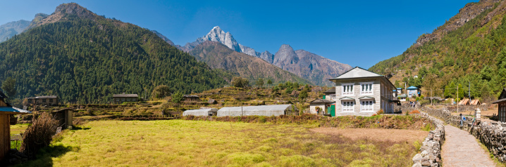 Nepali teahouses and lodges along the Mt. Everest Base Camp trail through the green forested foothills of the Khumbu valley under panoramic high altitude Himalayan skies. ProPhoto RGB profile for maximum color fidelity and gamut.