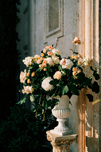 Bouquet of flowers stands on a pedestal in a vase near the wall of an ancient building. High quality photo