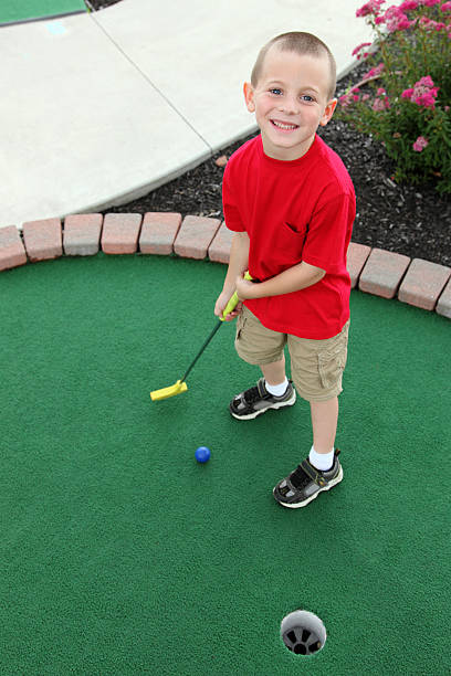 istock Cute little boy playing mini golf ready to putt ball 182804922