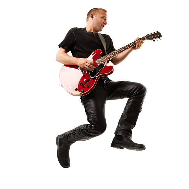 Man Jumping Through Midair While Strumming Electric Guitar. White Background. stock photo