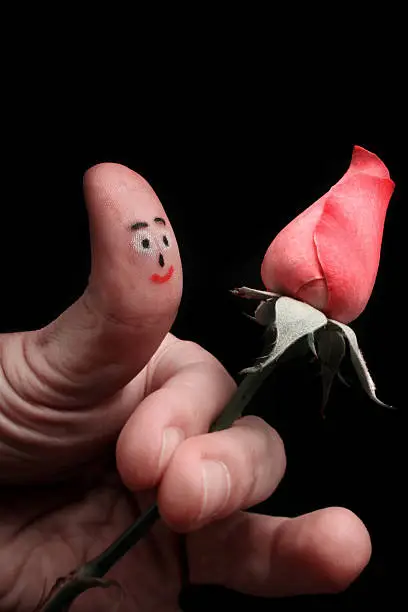 Fingerman puppet (Face drawing on the thumb) holding the pink rose.