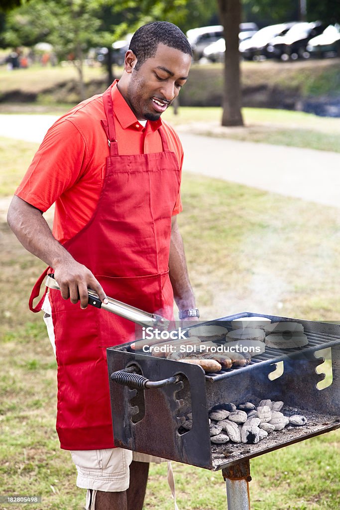 Afro-americano homem de churrasco, hambúrgueres, cachorros-quentes e salsichas - Foto de stock de Grelhado - Cozido royalty-free