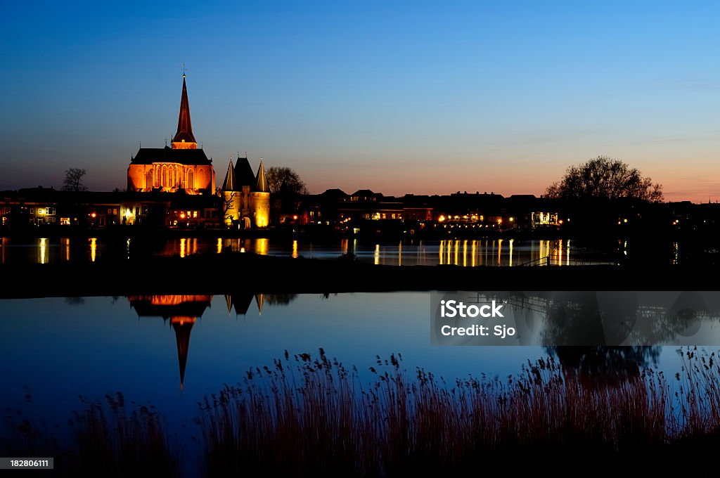 Church and tower by Night The Bovenkerk and Korenmarktpoort in the city of Kampen, The Netherlands at night. The church and gate are reflected in the water of the river IJssel. Cathedral Stock Photo