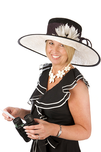 A woman holding binoculars and a betting slip dressed up for a day at the races. One of a series of images.