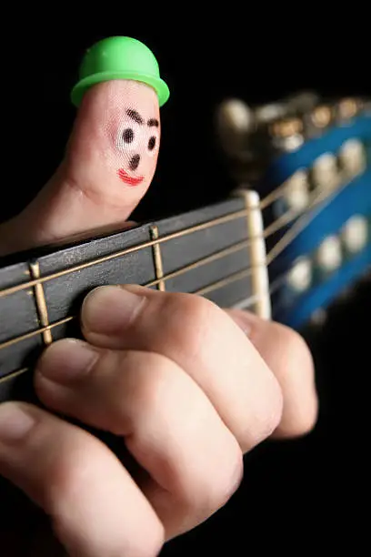 Fingerman puppet (Face drawing on the thumb) playing guitar.