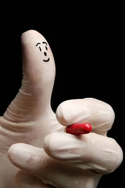 The fingerman doctor puppet (Face drawing on the thumb) is holding a pill.