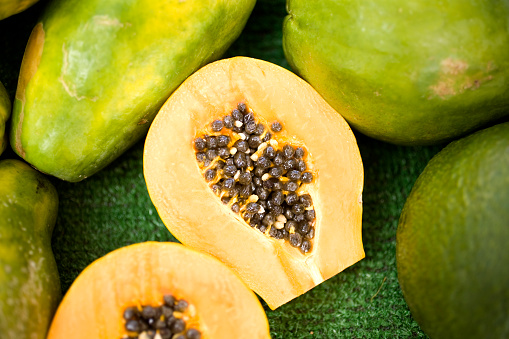 Papayas on display, with one cut in half to show the inside of the fruit, at the farmer's market in Honolulu, HI.