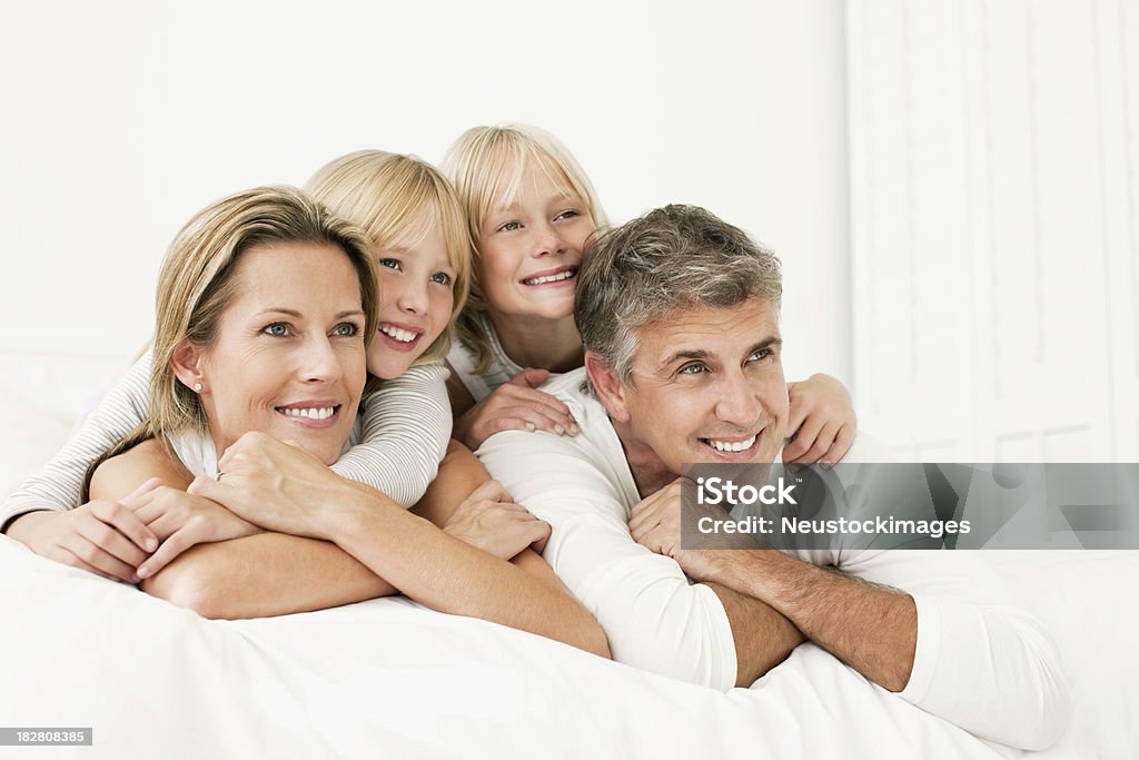 Família deitado em uma cama e sorrindo - Foto de stock de 30 Anos royalty-free