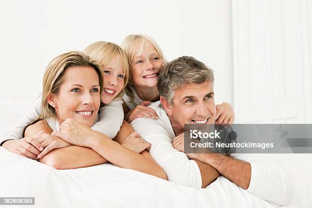 Foto de Família Deitado Em Uma Cama E Sorrindo e mais fotos de stock de 30 Anos - 30 Anos, Abraçar, Adulto