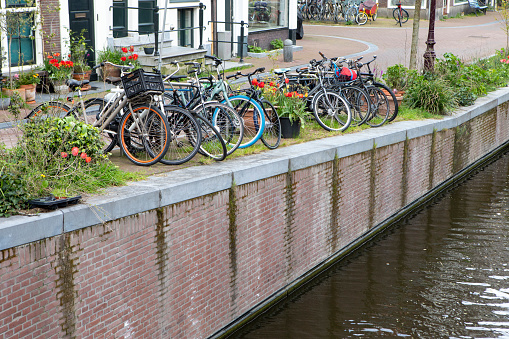 Amsterdam, Netherlands - September 7, 2018: Old traditional leaning houses along a canal with many bicycles parked and people around in Amsterdam, Netherlands