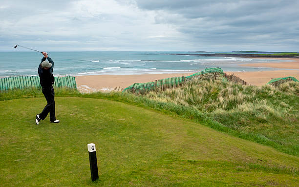 istock Man swinging club while golfing by the ocean in Ireland 182808940