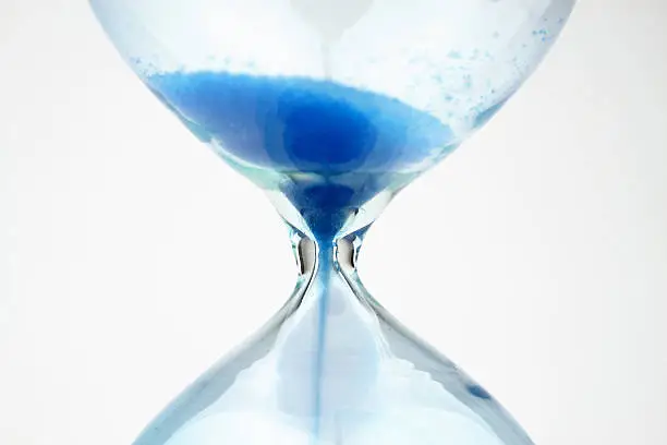 Photo of Close-up of an hourglass with blue sand