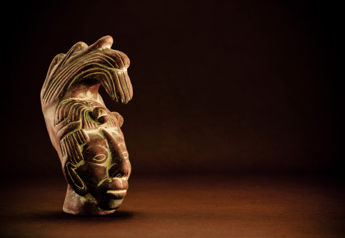 mayan terracotta head on dark brown background