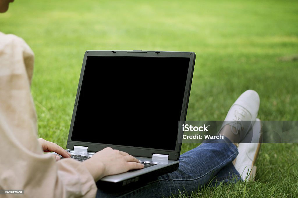 Giovane donna sull'erba nel parco con il portatile - Foto stock royalty-free di Adulto