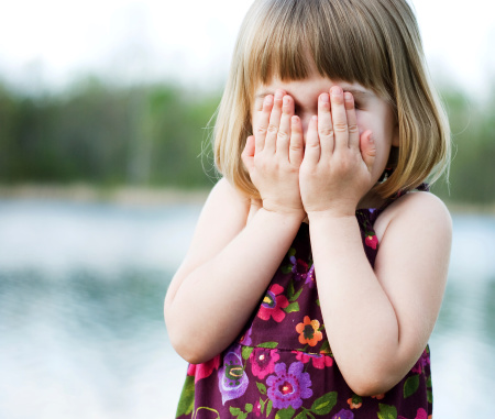 Color image of a Little girl covering her eyes.