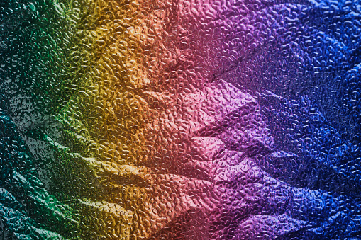 Rainbow gradient textural Background. Wrinkled folded paper or foil.