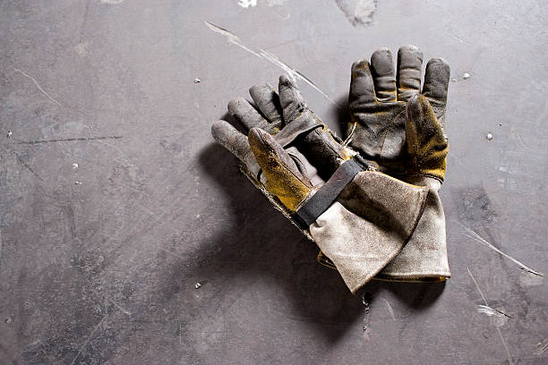 die handschuhe tragen auf beton boden liegen - arbeitshandschuh stock-fotos und bilder