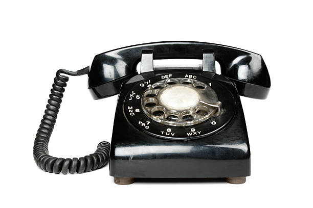 A black vintage rotary dial telephone A black rotary telephone, isolated on a white background. landline phone stock pictures, royalty-free photos & images