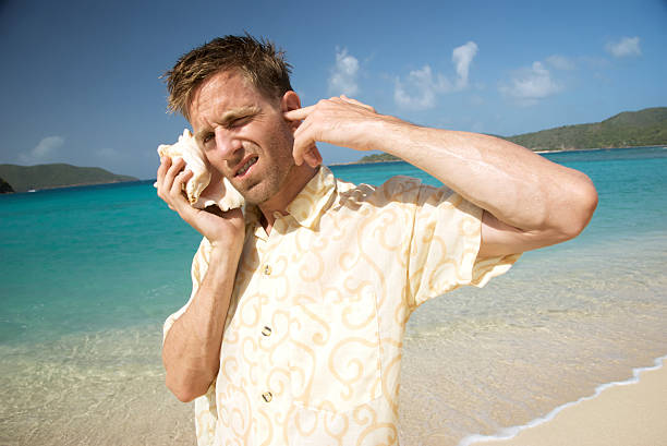 turista toma de una llamada con su teléfono de carcasa - stranded men telephone beach fotografías e imágenes de stock