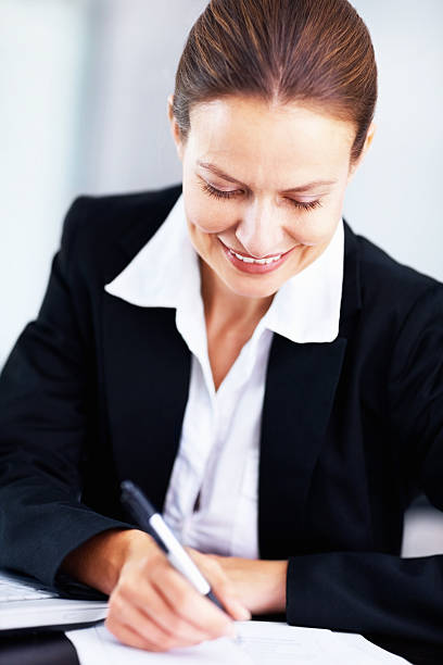 istock Happy business woman sitting at a table writing notes 182812834