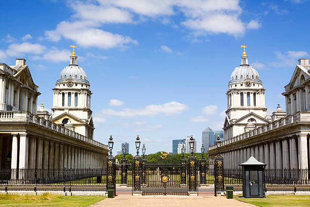 Old Royal Naval College Greenwich "The Old Royal Naval College is the architectural centrepiece of the World Heritage Site at Greenwich, London, situated on the south bank of the River Thames. Designed by architect Sir Christopher Wren the Old Royal Naval College,was originally Greenwich Hospital from 1873, before closing and becoming the Royal Naval College in 1998. The domed building on the right is Queen Mary Court and on the left is the domed  building of King William Court. One cupolas has a clock dial, the other a compass dial. Between the buildings the Greenwich Meridian passes. In the distance is the City of London and Canary Wharf centres of commerce. Good copy space,." greenwich london stock pictures, royalty-free photos & images