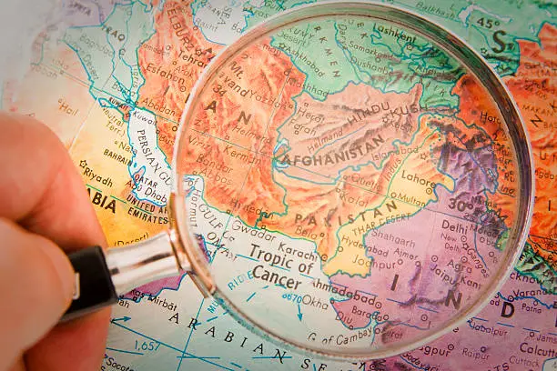"Studying Geography - Photograph of Afghanistan, Pakistan and surrounding countries  on retro globe underneath a magnifying glass."