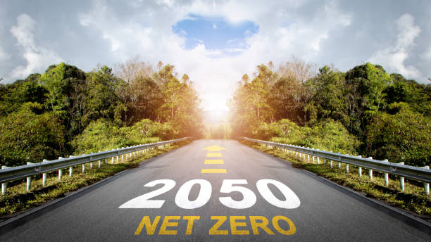 istock Net zero by 2050. Text Net Zero 2050 with arrow symbol written on the road in the middle of asphalt road with at sunset.Net zero greenhouse gas emissions target. Climate neutral long term strategy. 1828132210
