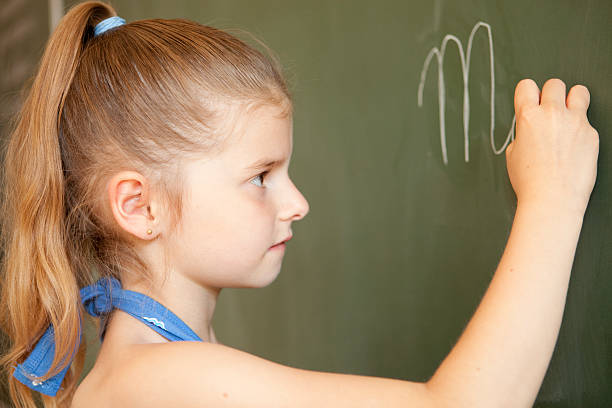 istock Young female child writing on blackboard 182813249