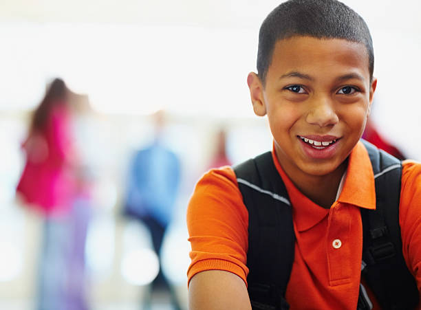 African American school boy with friends in the background Close-up of a smiling African American school boy with friends in the background cute 15 year old girls stock pictures, royalty-free photos & images