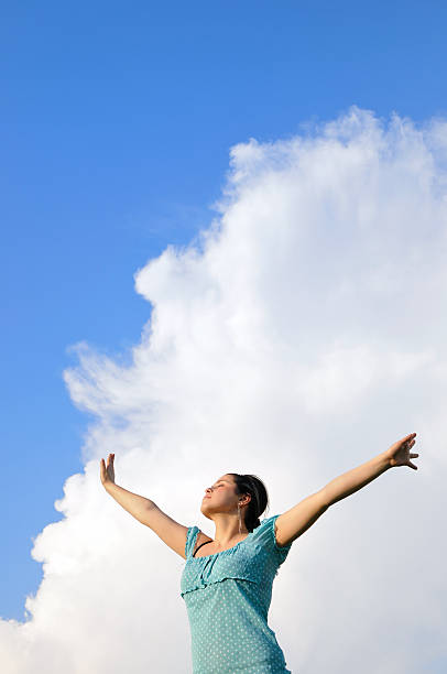istock Woman with raised hands and blue sky behind her 182813552