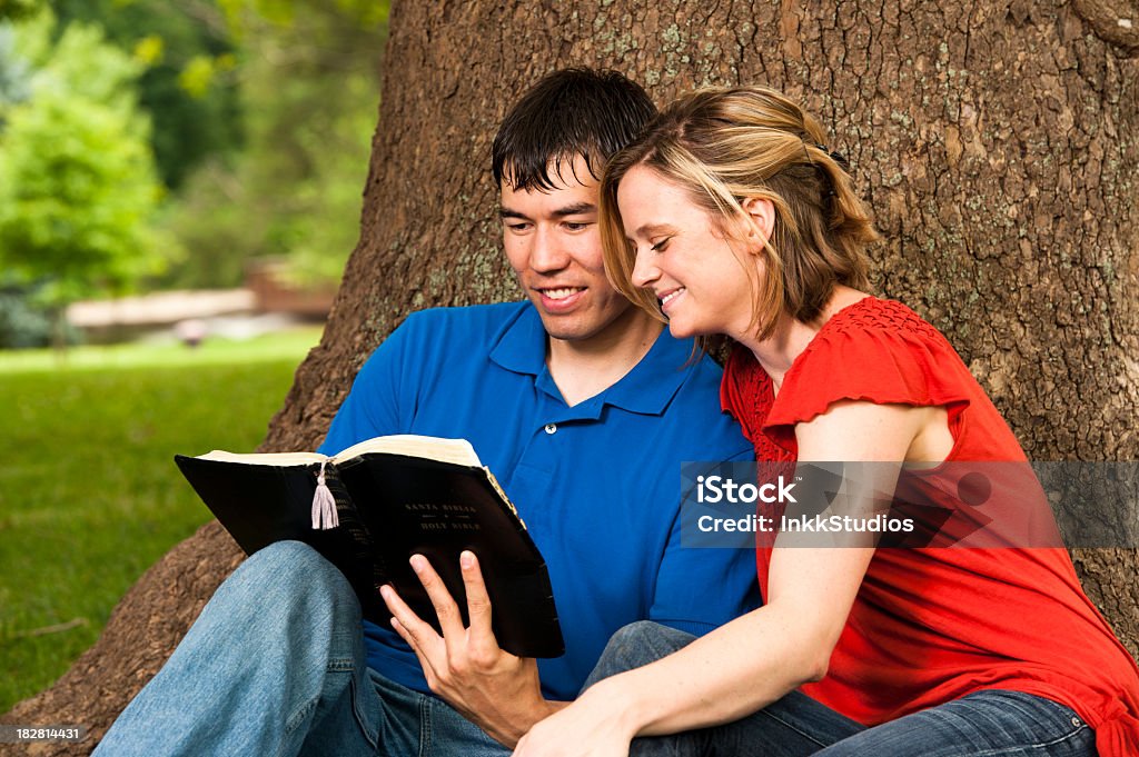 Young Man and Woman reading the Bible in a park. 20-29 Years Stock Photo