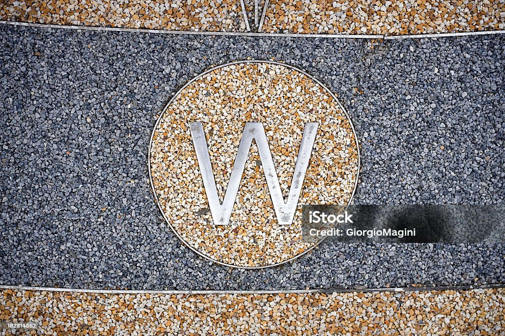 Letter W for West on Granular Exterior Floor The letter W to indicate the West in a large compass rose on an exterior floor in Italy. Alphabet Stock Photo