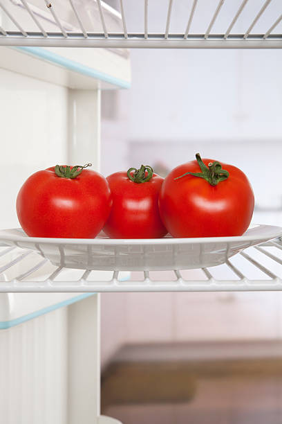 three tomatoes in fridge stock photo