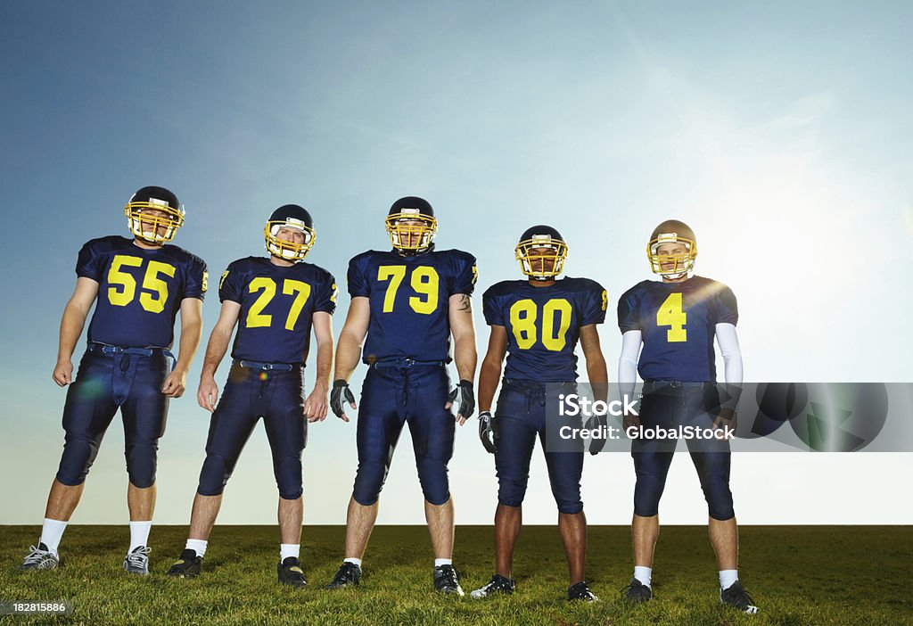 Pro American futbolistas de pie contra el cielo despejado - Foto de stock de Equipo de fútbol americano libre de derechos