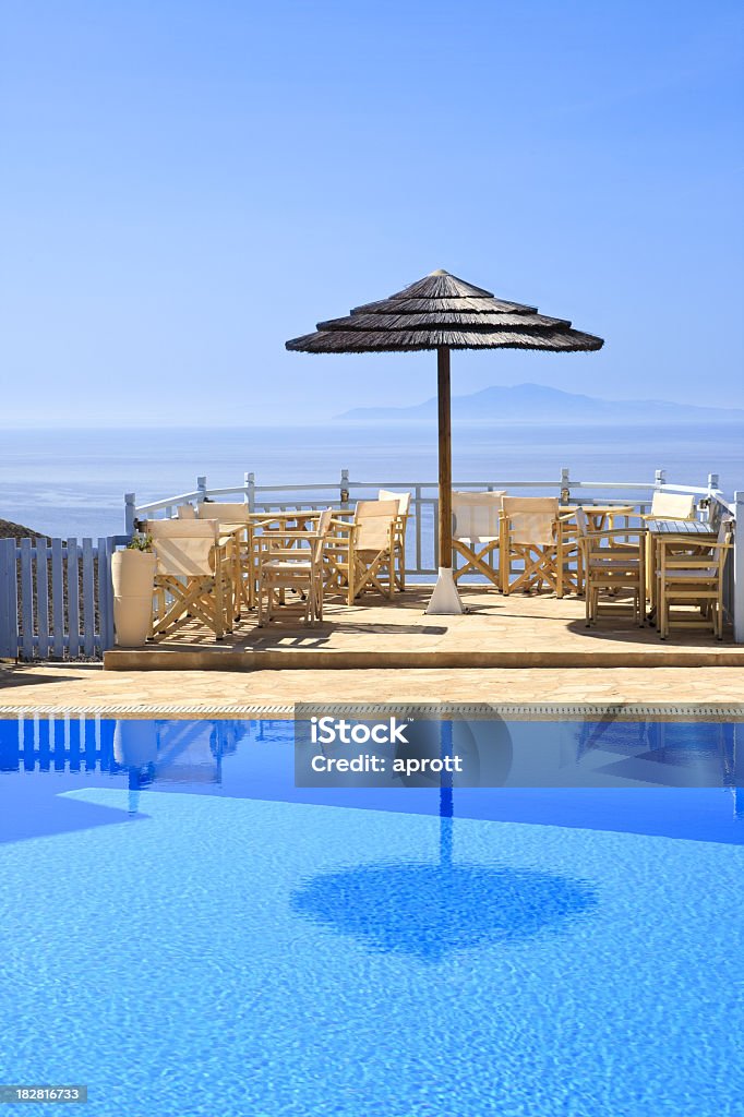 Swimming pool and balcony on cyclades Swimming pool and balcony in front of the Mediterranean Sea. In the background the island Sifnos, part of the Cyclades island group. Parasol reflecting in the pool. Copy space. Balcony Stock Photo