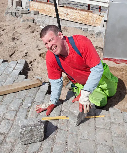 Paver working on his knees setting granite paving stones, Stockholm, Sweden.