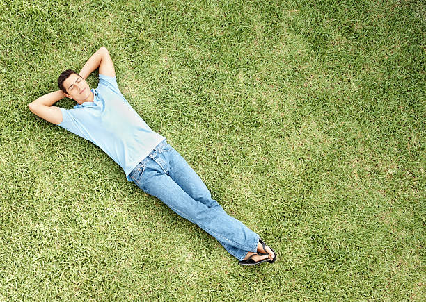 détendue jeune homme dormir sur de l'herbe - supine photos et images de collection