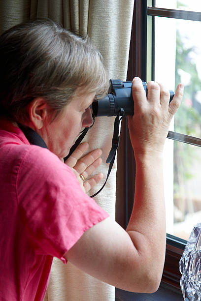 istock Nosey neighbour at the window with binoculars 182818528